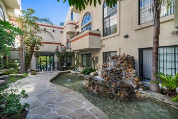 A stone fountain is in the middle of a courtyard.