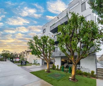 A modern building with a white exterior and a green lawn in front.