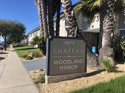 A sign for Chateau Woodland Manor is displayed in front of a building.