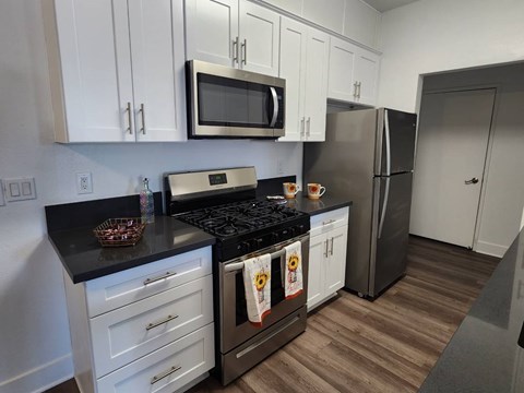 A kitchen with white cabinets and a black countertop.