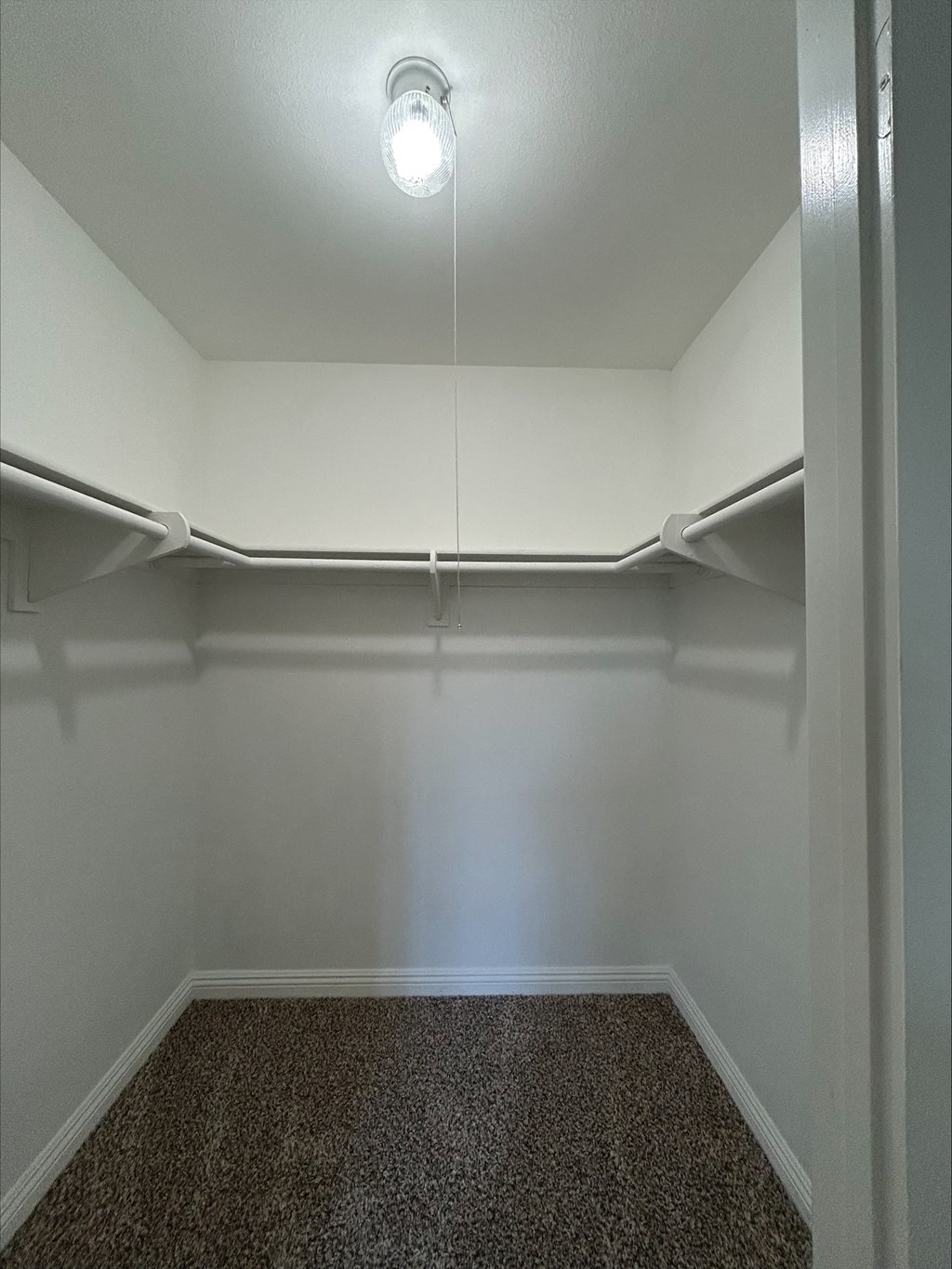 A small, empty room with a single light bulb on the ceiling.