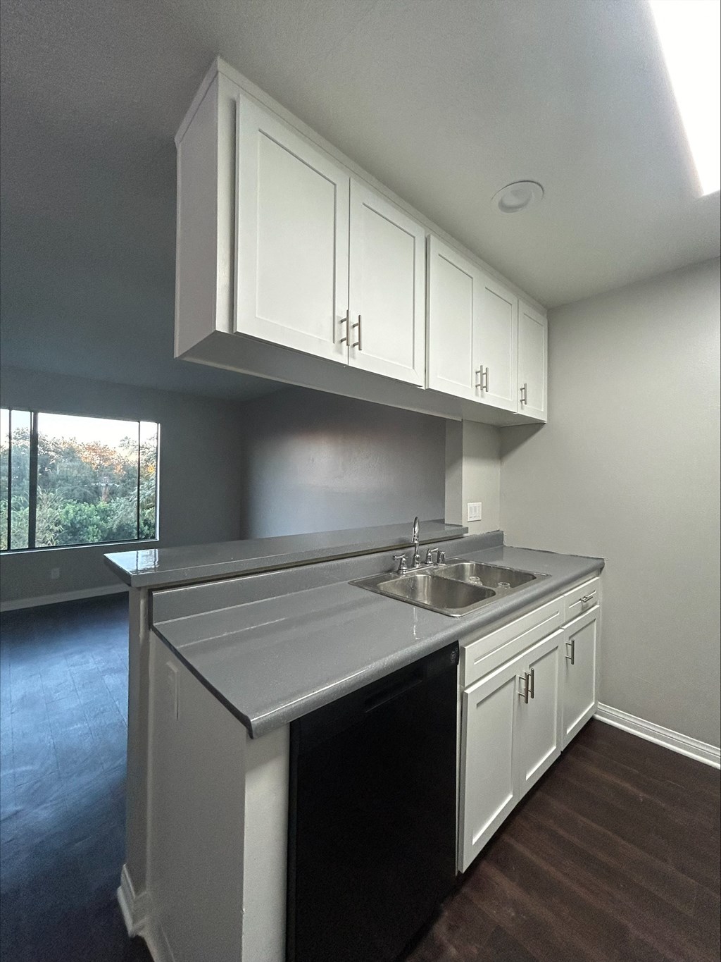 A kitchen with white cabinets and a black dishwasher.