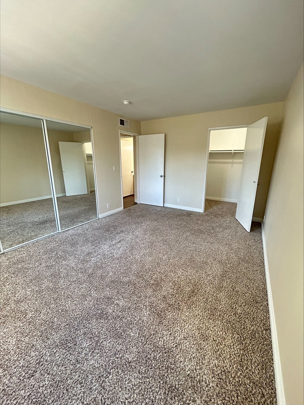 A room with carpeted floor and sliding glass doors.