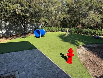 A red fire hydrant sits on a green lawn next to a brick walkway.