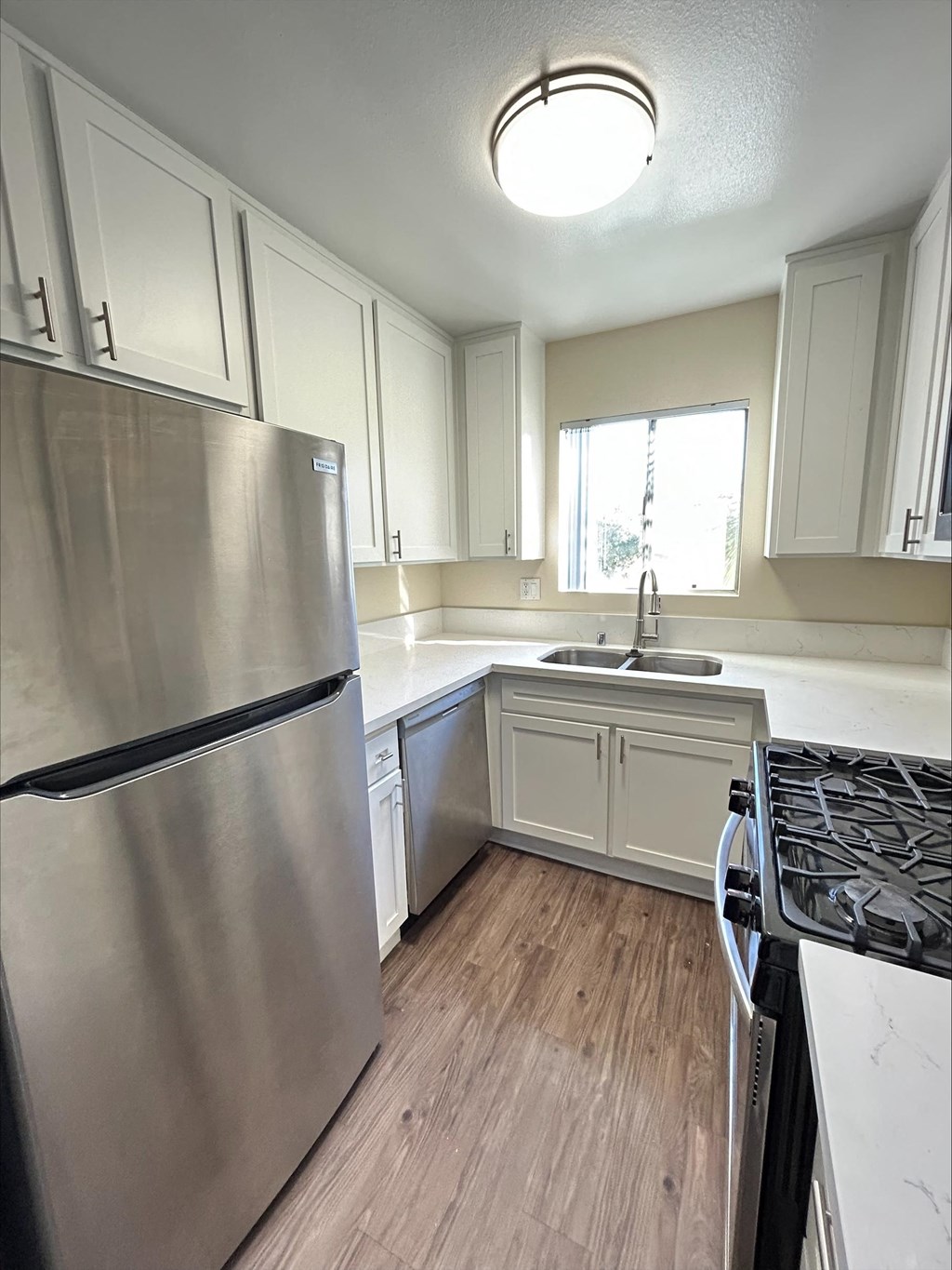 A kitchen with a stainless steel refrigerator and wooden floors.