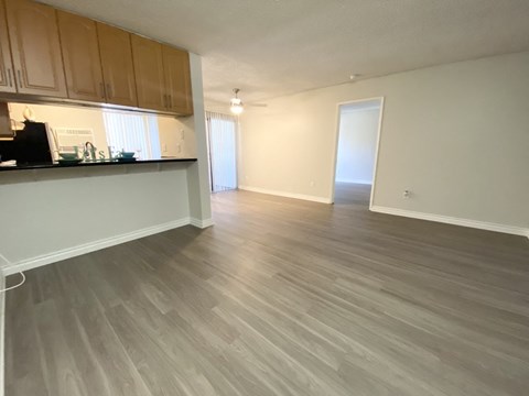 an empty living room and kitchen with wood flooring