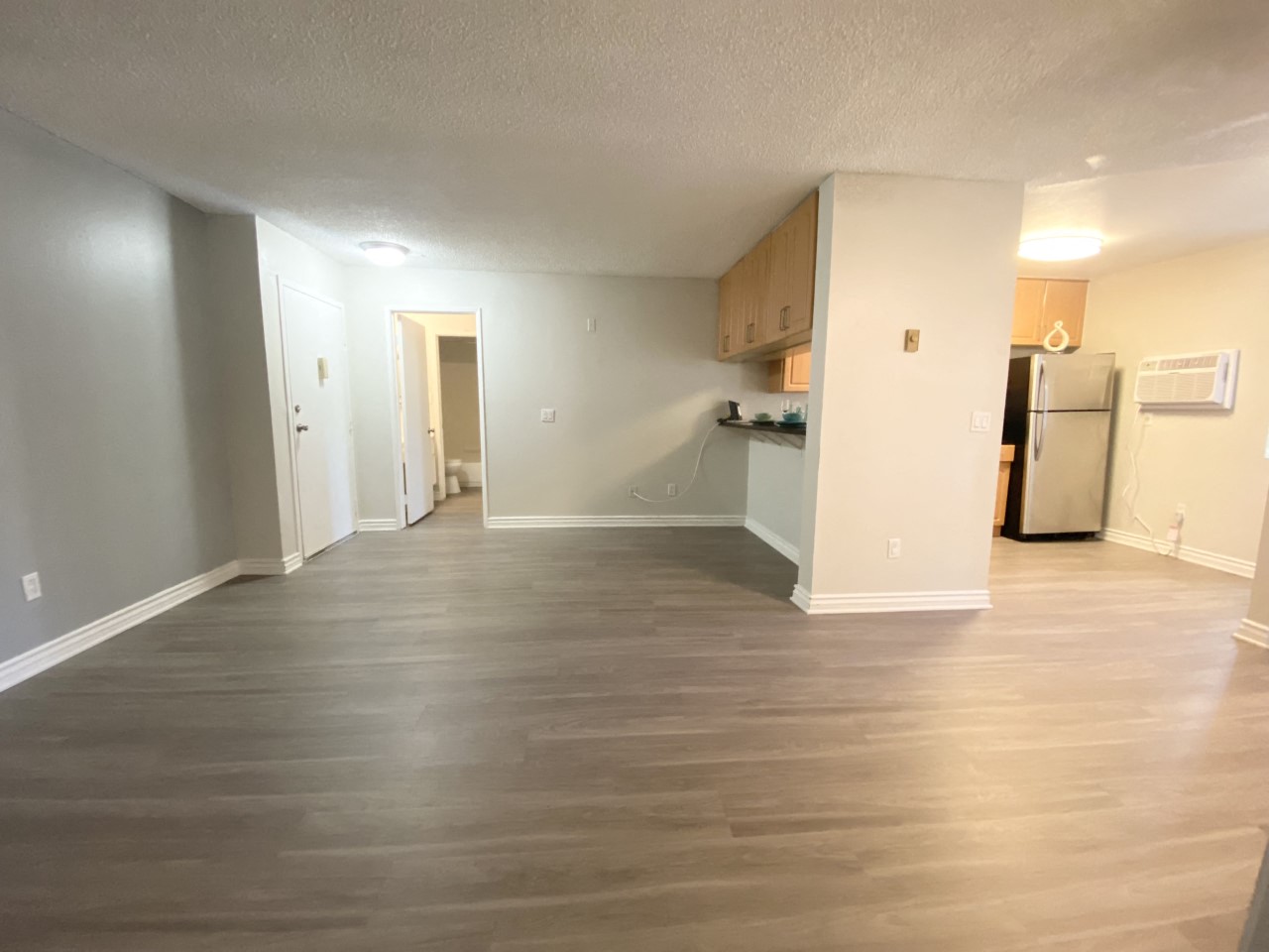 an empty living room and kitchen with a wood floor
