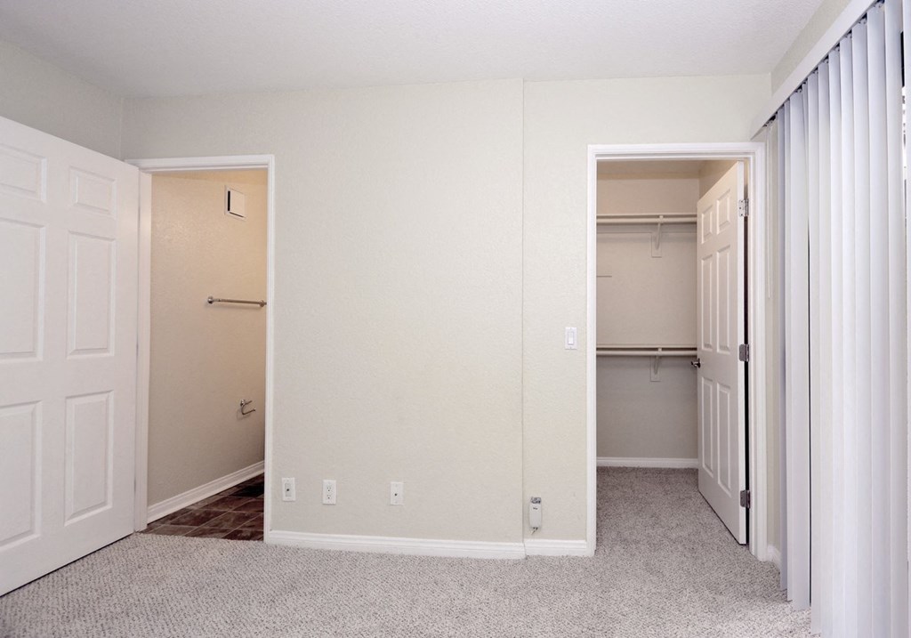 an empty bedroom with a closet and a mirrored closet door