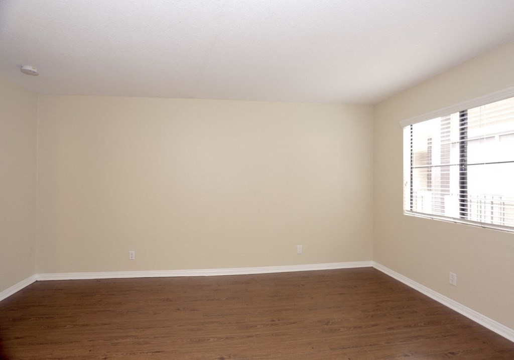 an empty living room with wood floors and a large window