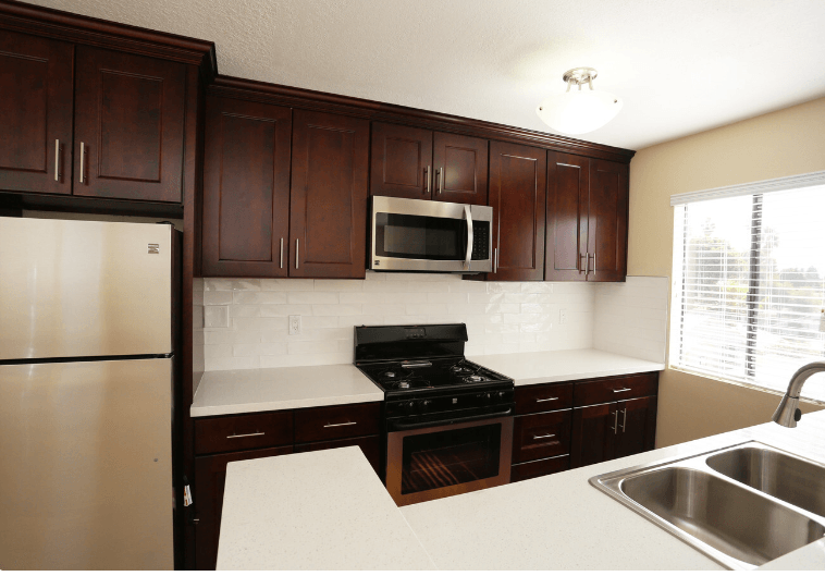 a kitchen with dark cabinets and a sink and a refrigerator