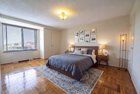 Bedroom with wood floors and blue area rug at 4000 Massachusetts Avenue Apartments, Washington, District of Columbia