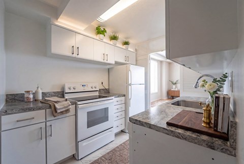 A kitchen with white cabinets and a marble countertop.