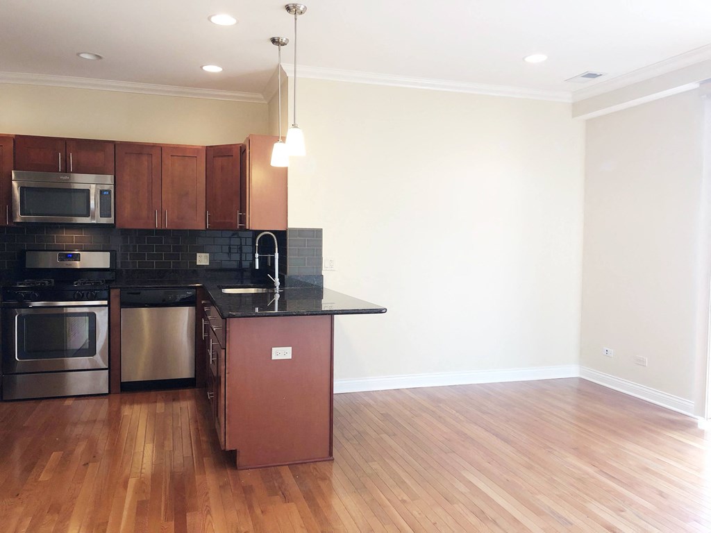 a kitchen with wood floors and a black counter top
