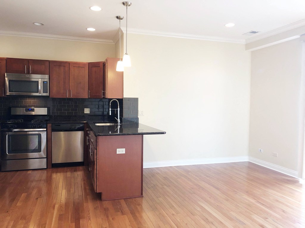 a kitchen with wood floors and a black counter top
