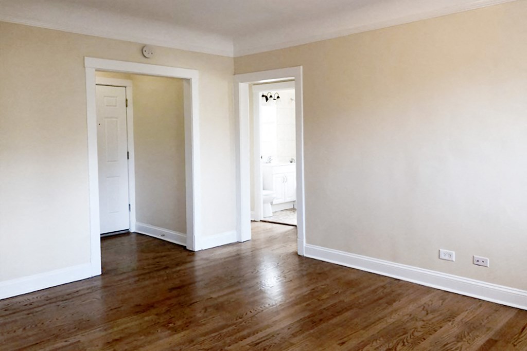 a bedroom with hardwood floors and white walls