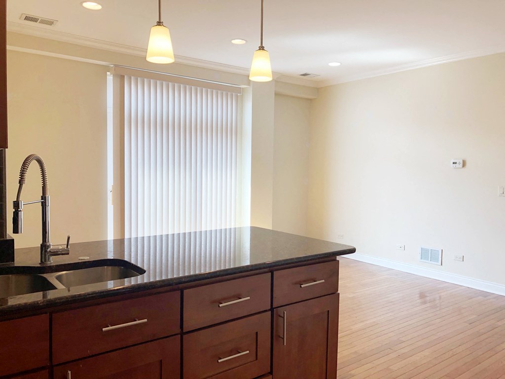 a kitchen with an island and a living room in the background