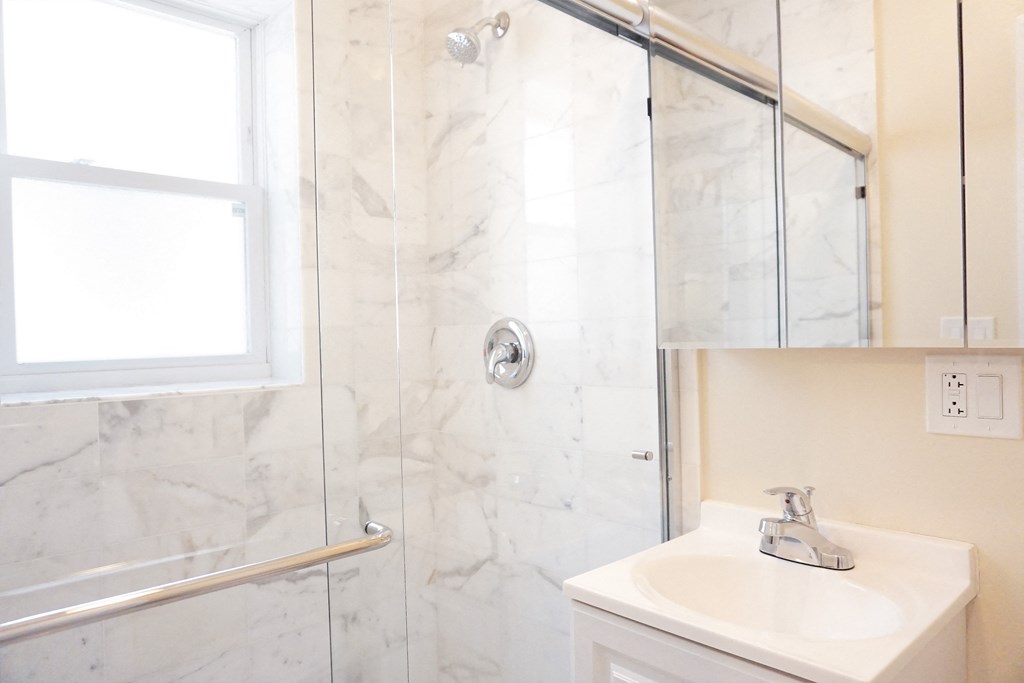 a bathroom with a white sink and a shower with a glass door