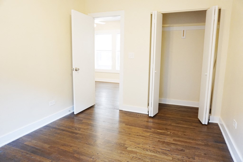 a bedroom with hardwood floors and white walls