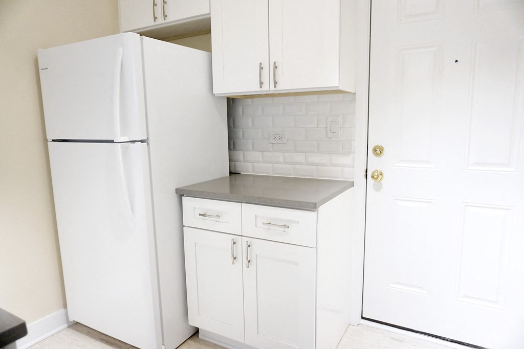 a small kitchen with white cabinets and a white refrigerator