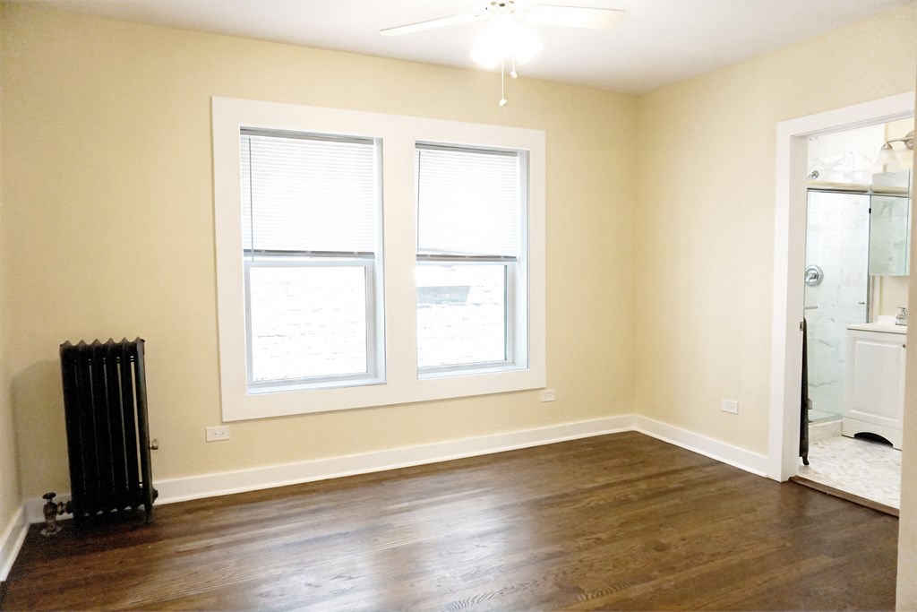 a bedroom with two windows and a radiator