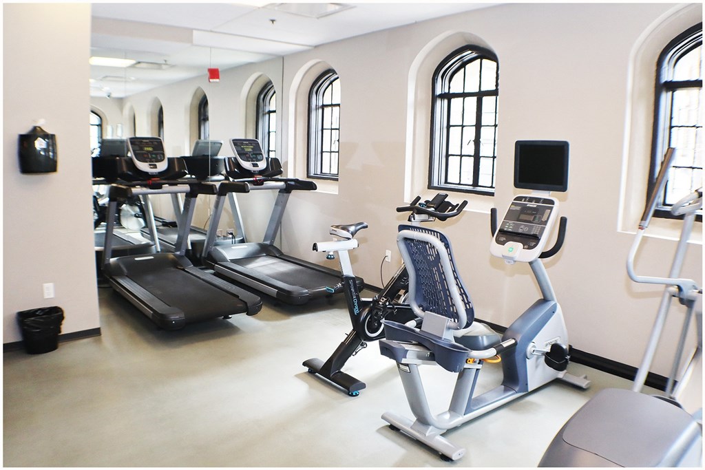 a row of treadmills and elliptical trainers in a gym