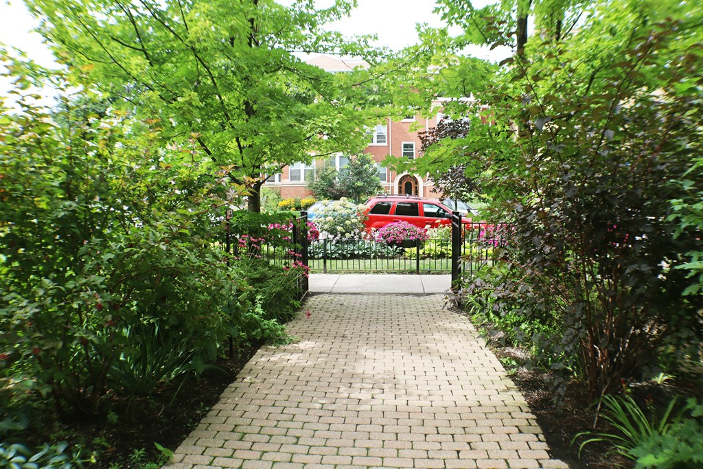 a walkway in front of a gate with a red car