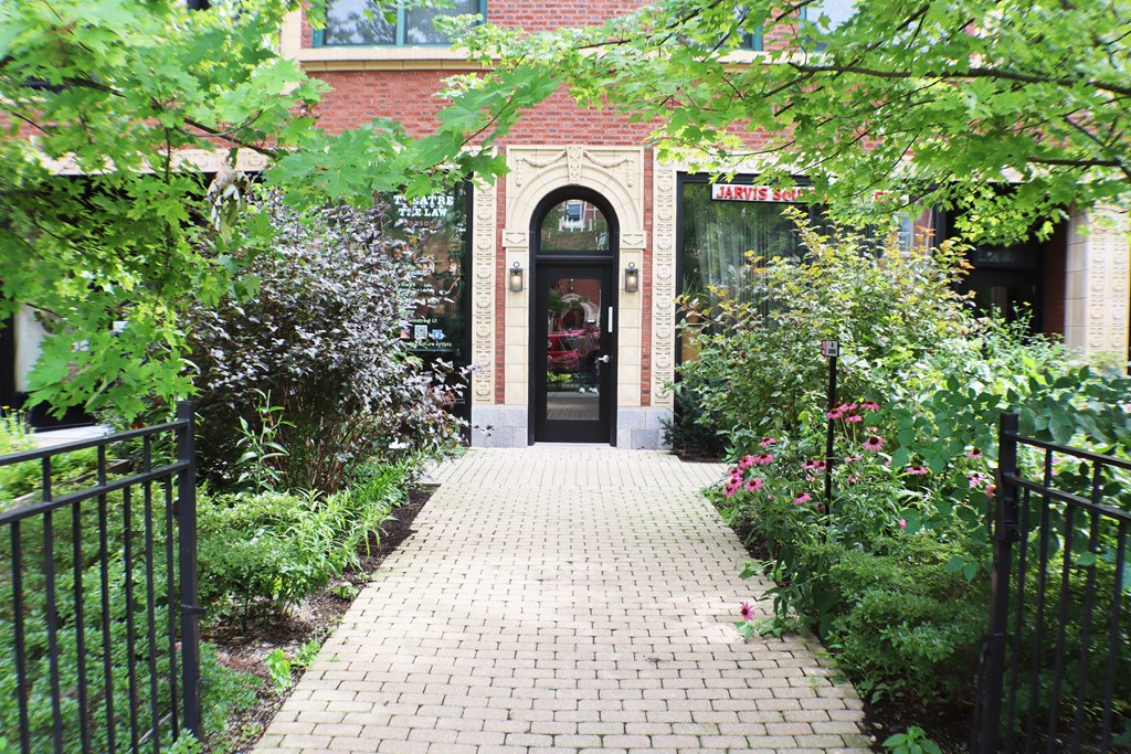 the entrance to a building with a brick sidewalk and plants