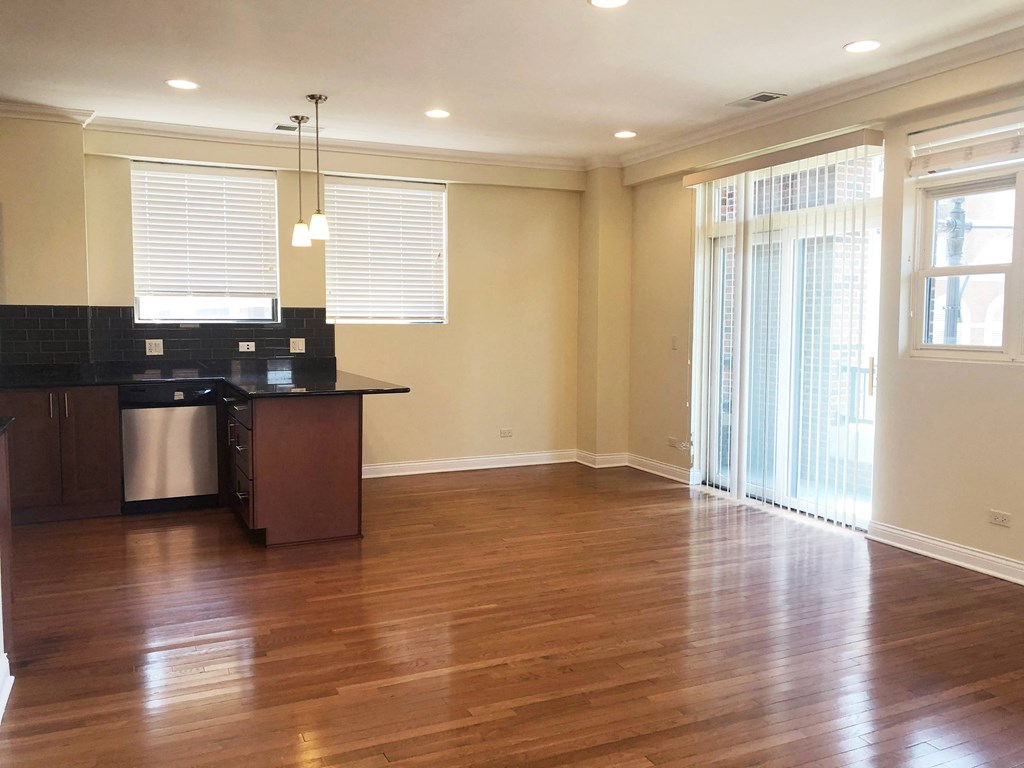 a kitchen and living room with wood floors and a sliding glass door
