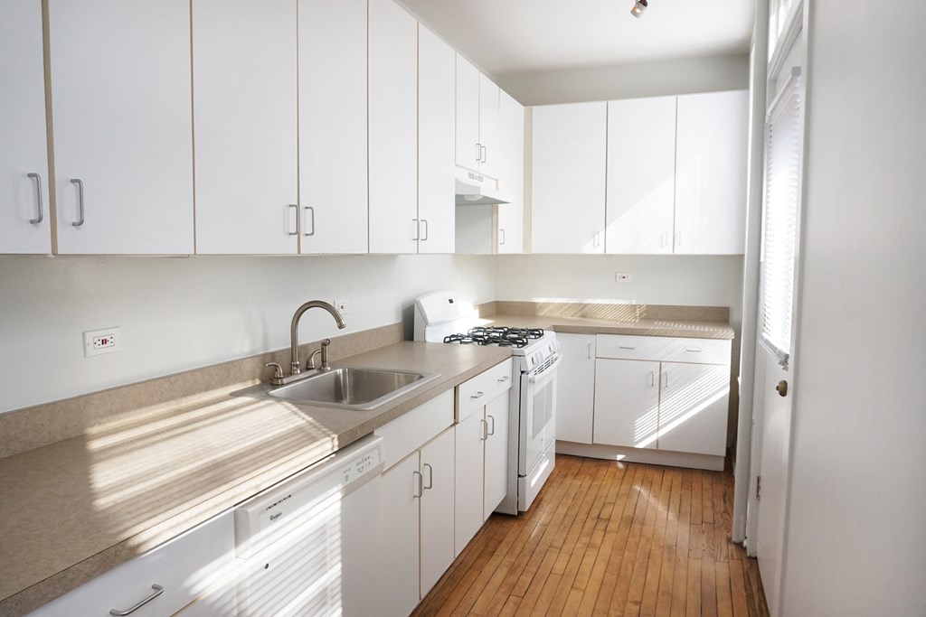 a kitchen with white cabinets and a wooden floor