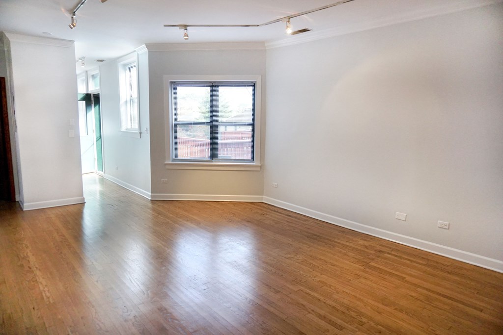 a bedroom with hardwood floors and a window