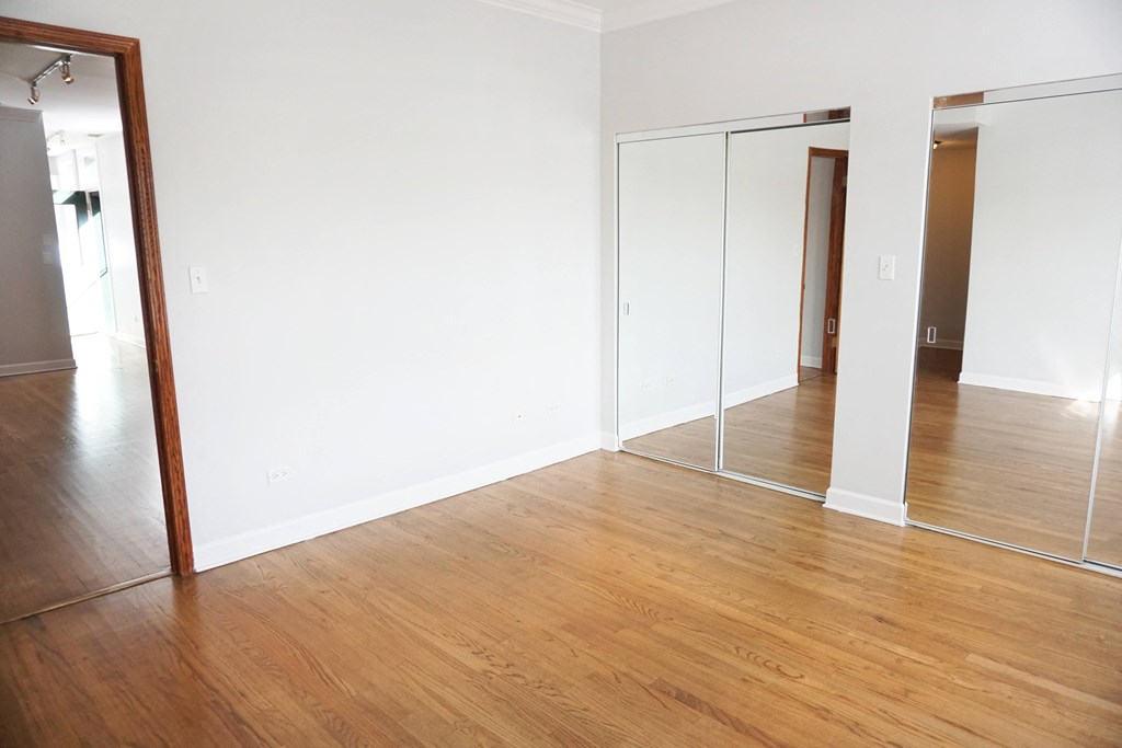a bedroom with white walls and a wooden floor