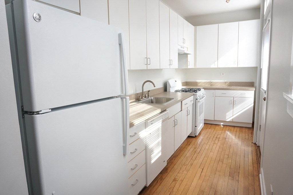 a kitchen with white cabinets and a wooden floor