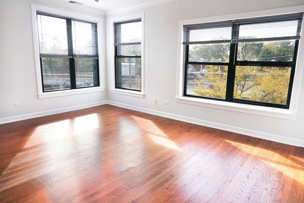 an empty living room with wood floors and windows