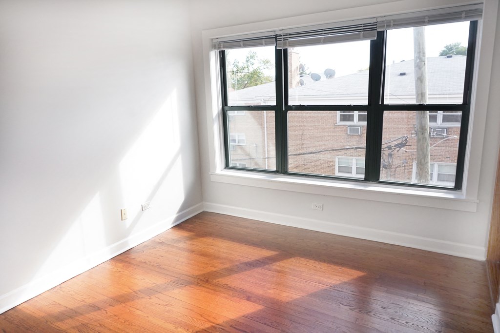 an empty room with a window and wooden floors
