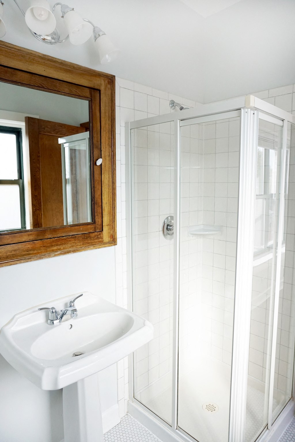 a white bathroom with a shower and a sink and a mirror