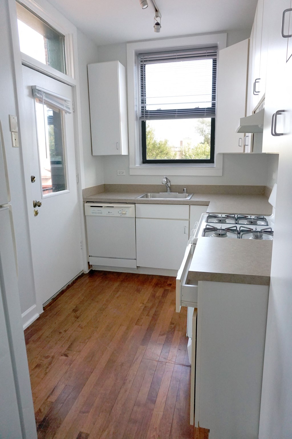 a small kitchen with white cabinets and a wood floor