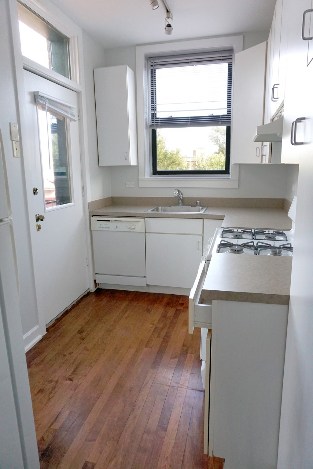 a small kitchen with white cabinets and a window