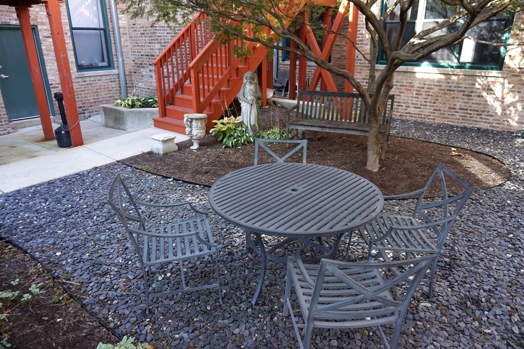 a patio with a table and chairs in front of a brick building