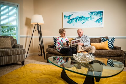 An older couple sitting on a couch in a living room.