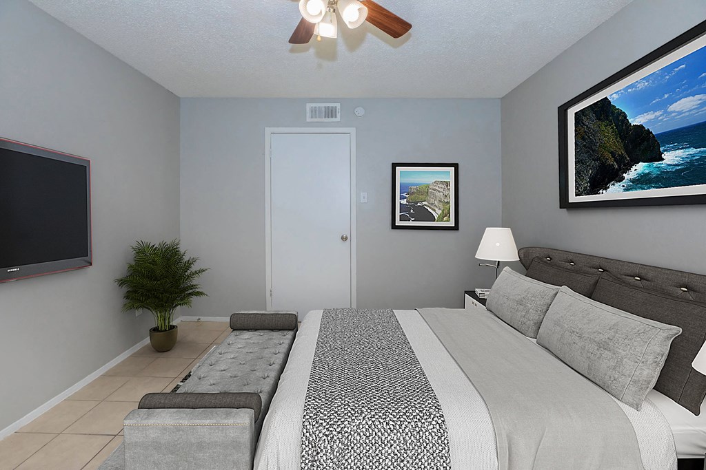 a gray bedroom with a large bed and a tv