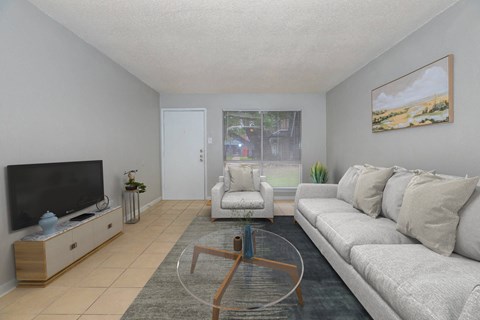 A living room with a grey couch, a coffee table, and a painting on the wall.
