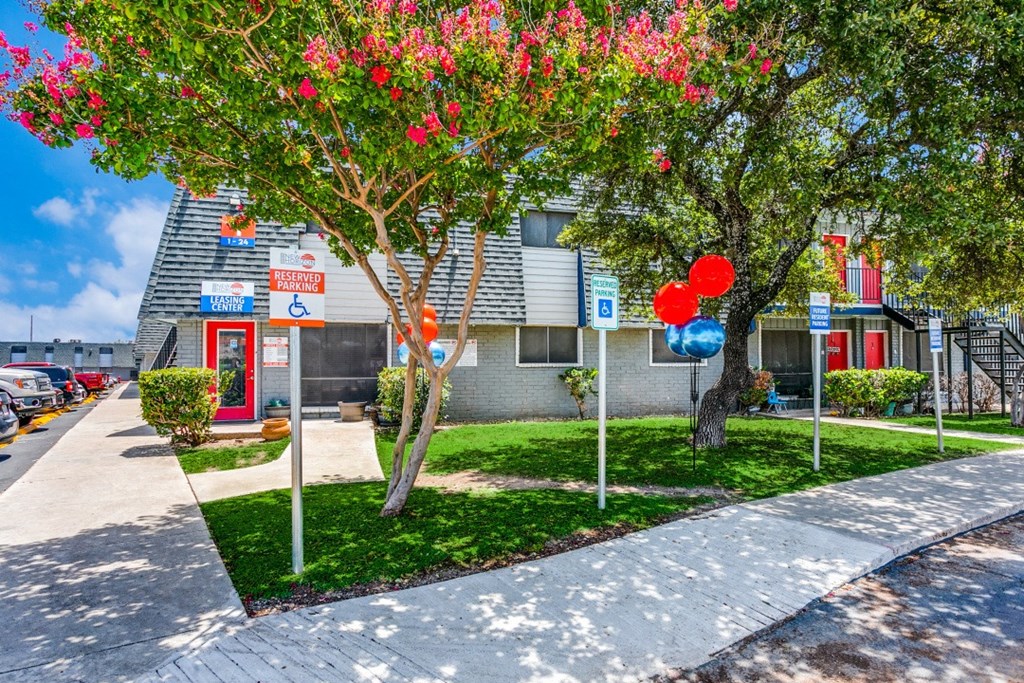 an apartment building with a sidewalk and trees in front of it