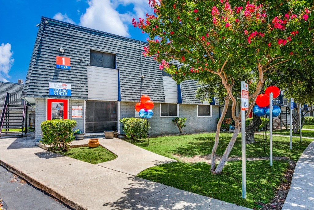 the front of a building with balloons and a sidewalk in front of it