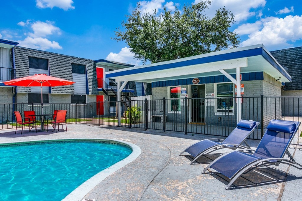 our apartments have a pool and a patio with chairs and a umbrella