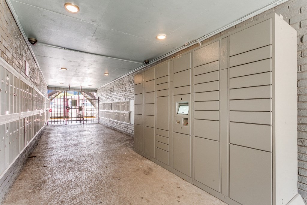A long hallway with a brick wall on the left and a metal gate in the distance.