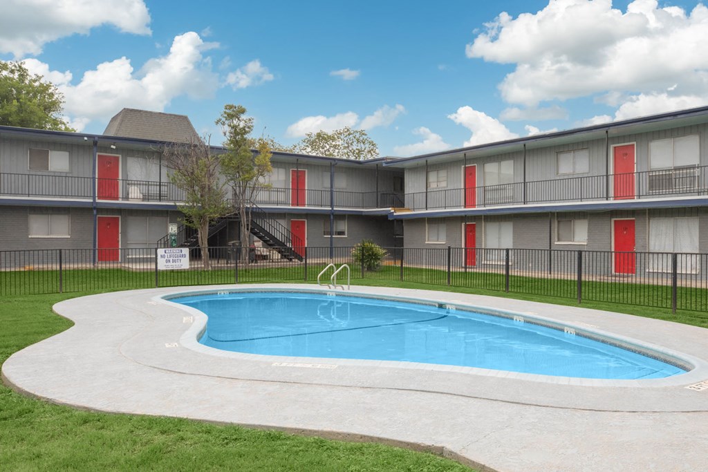 a swimming pool in front of an apartment building with a pool