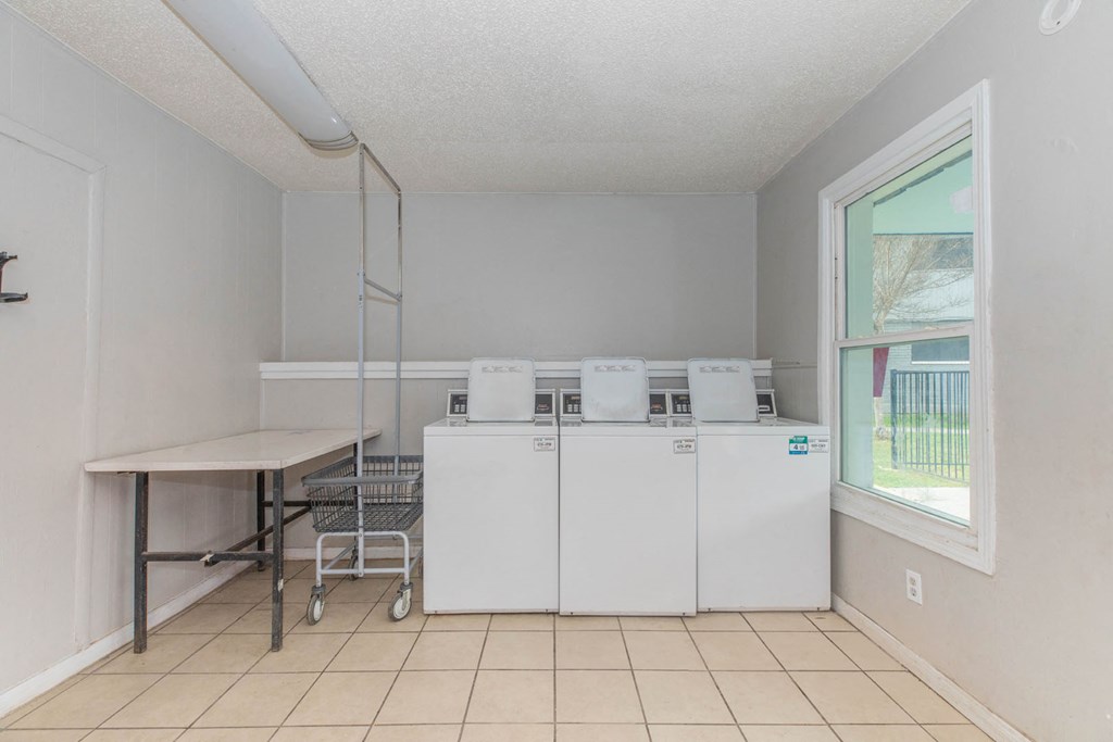 a laundry room with four washing machines and a table