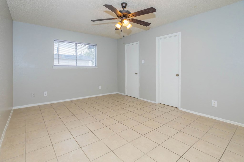 an empty living room with a ceiling fan and a tiled floor