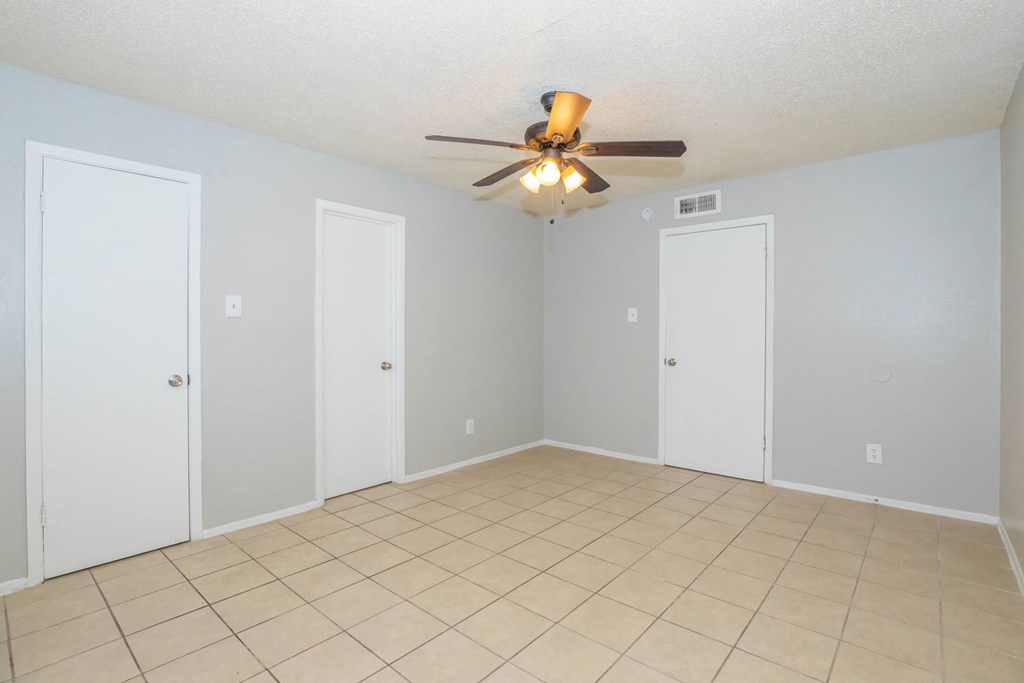 a empty living room with a ceiling fan and a tiled floor