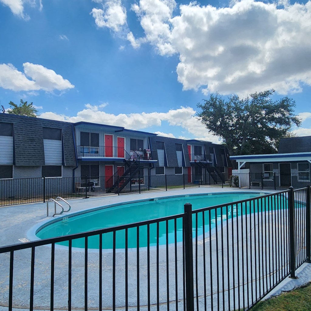 A black fence surrounds a green pool.